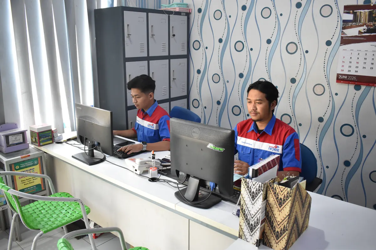 Dua staf customer service Percetakan Ivorie melayani pesanan cetak di meja kerja